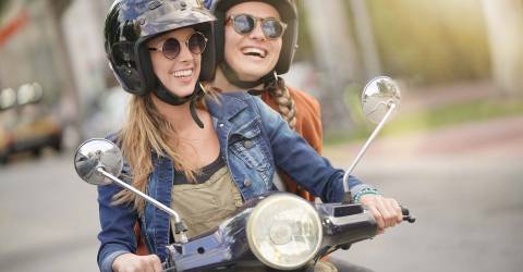 Twee jonge vrouwen rijden samen op een scooter